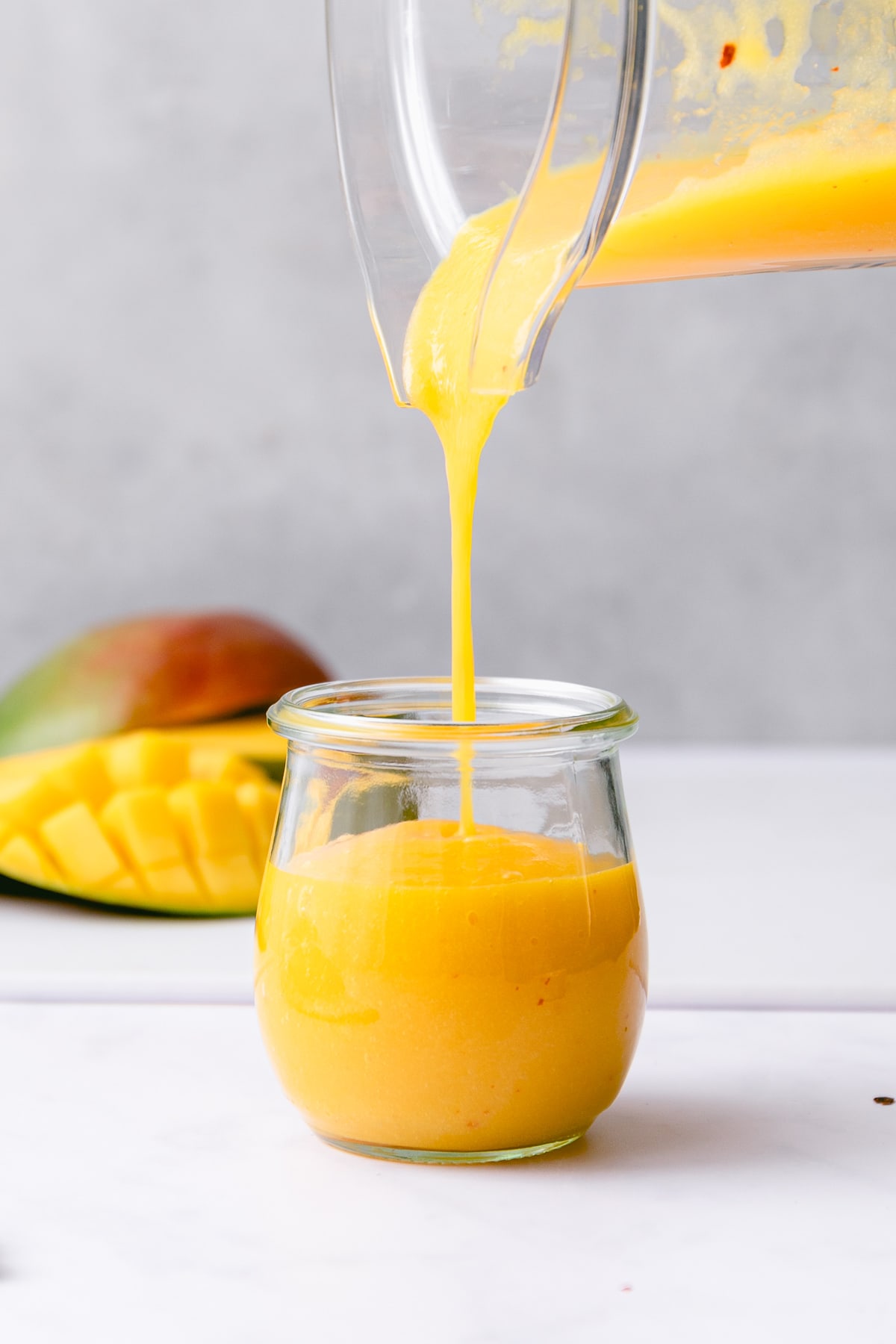 head on view of spicy mango dressing being poured into a glass jar.