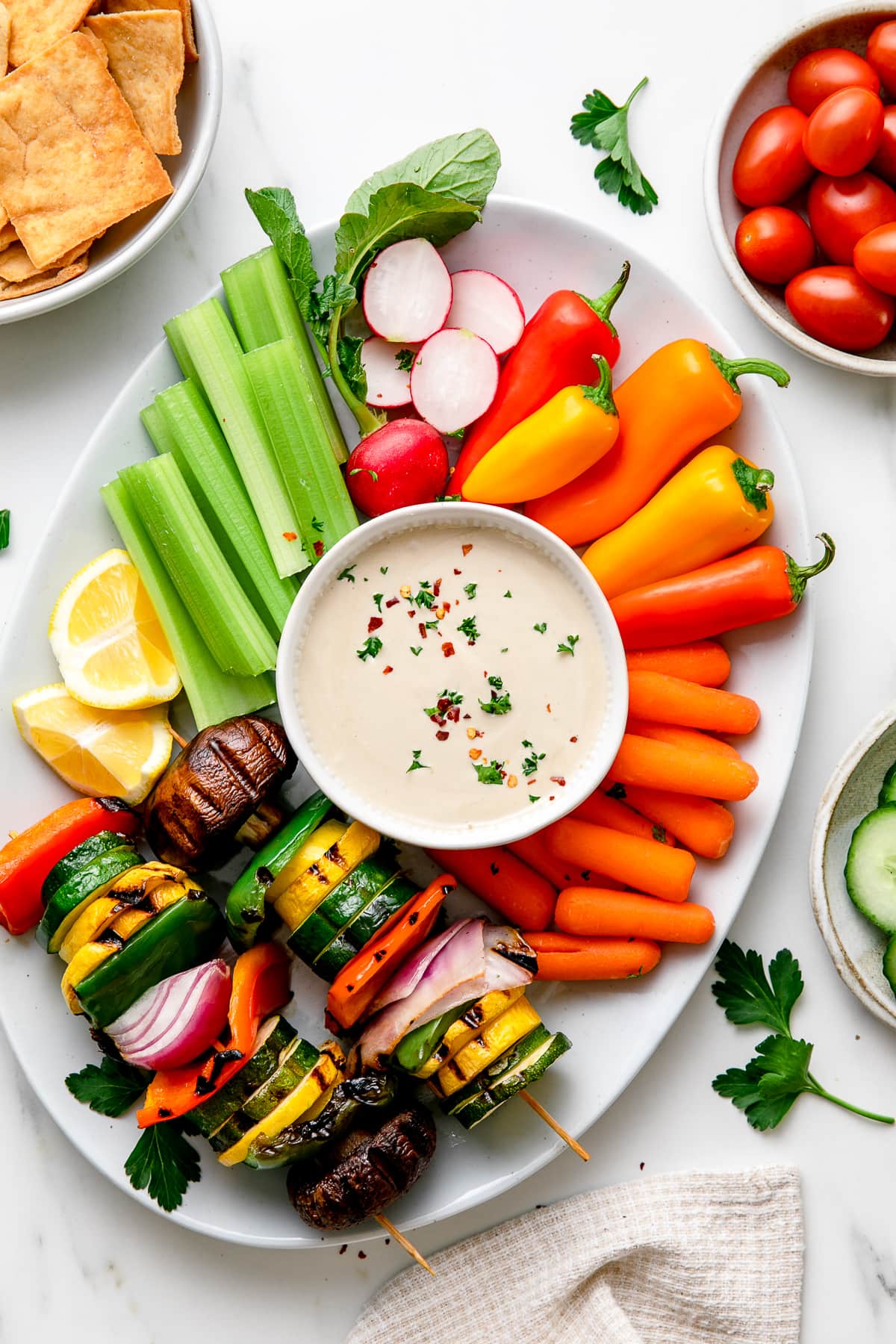 top down view of tahini sauce on a platter surrounded by vegetables.