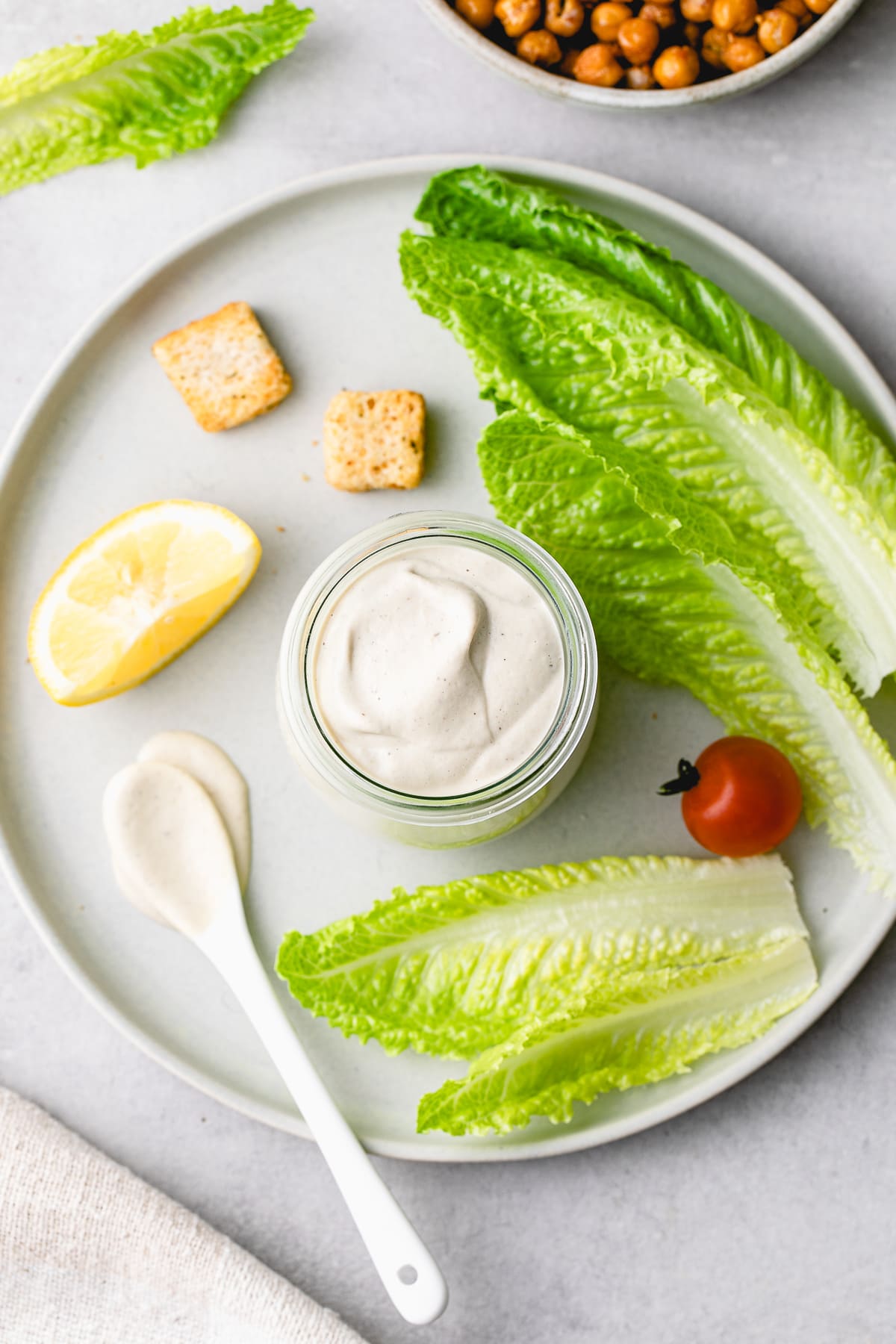 top down view of vegan caesar dressing in a glass jar with items surrounding.