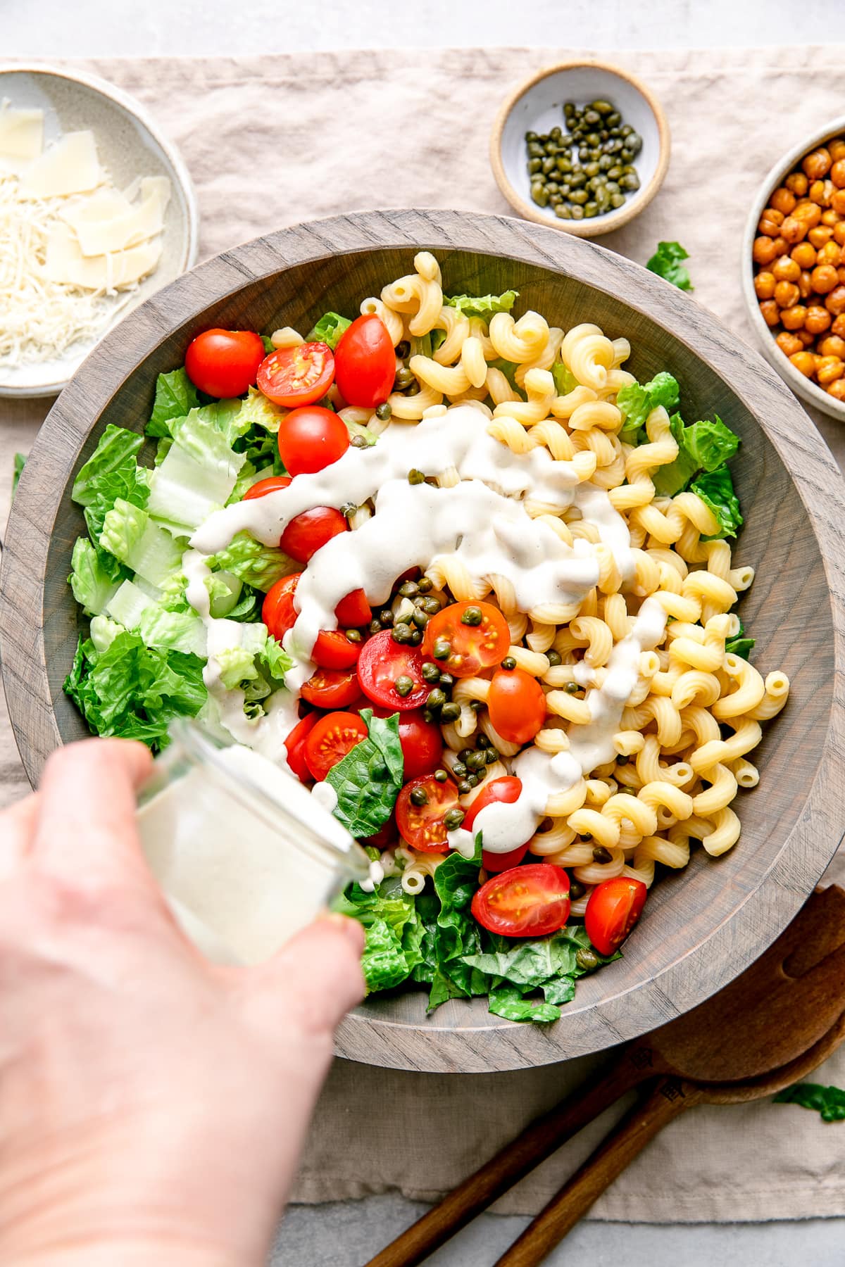 top down view of caesar dressing being poured over top pasta salad.