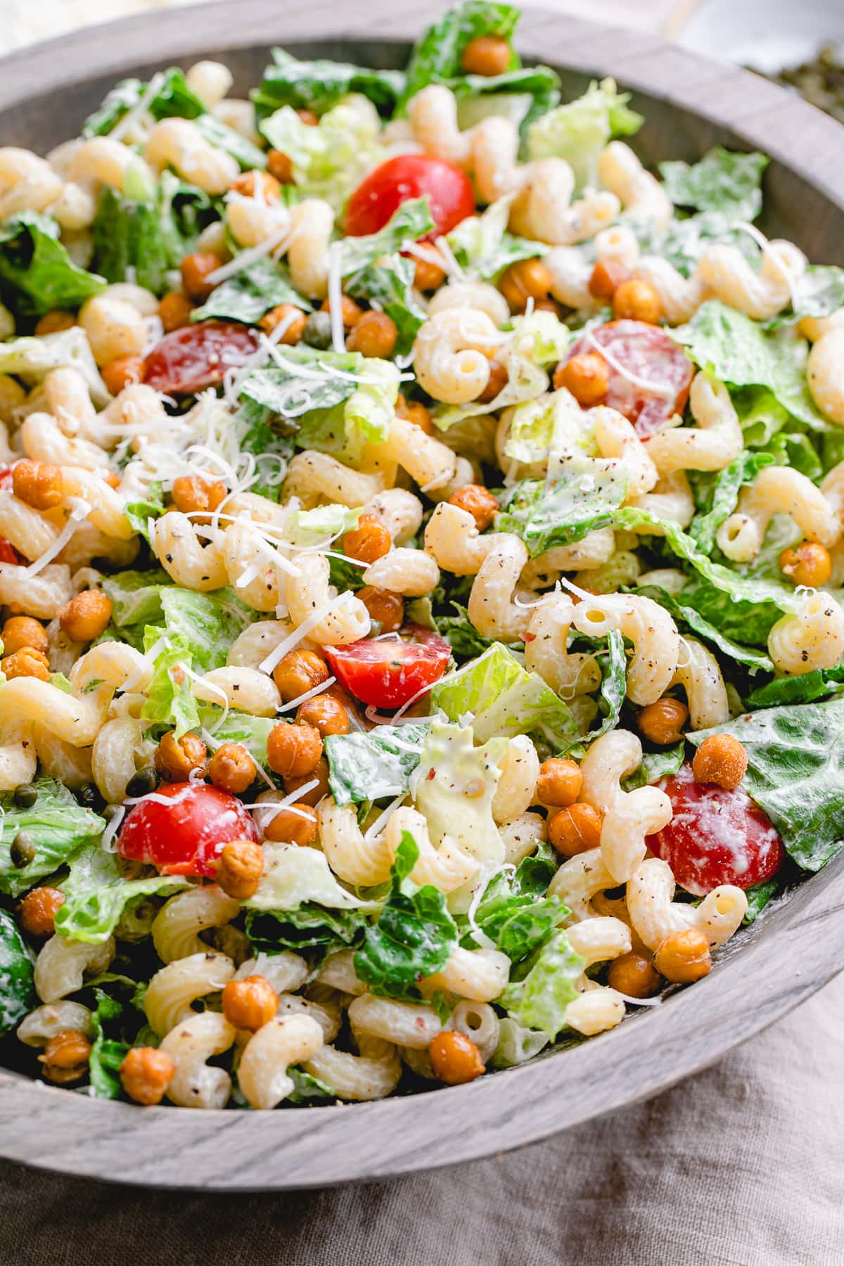 side angle view of caesar pasta salad in a large wooden bowl.