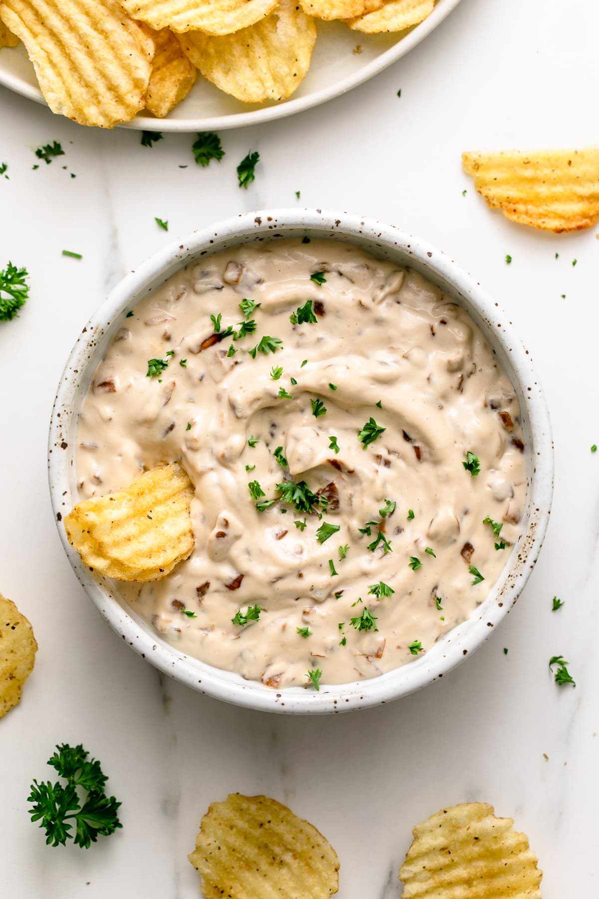 top down view of vegan french onion dip in a small bowl with chips surrounding.