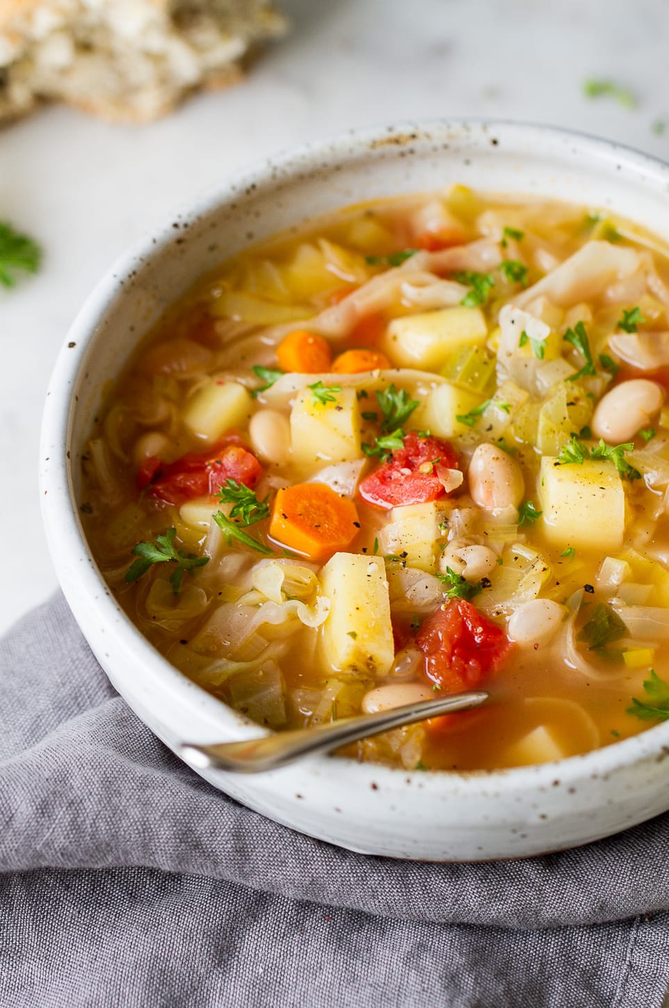 side angle view of potato cabbage white bean soup in a bowl.