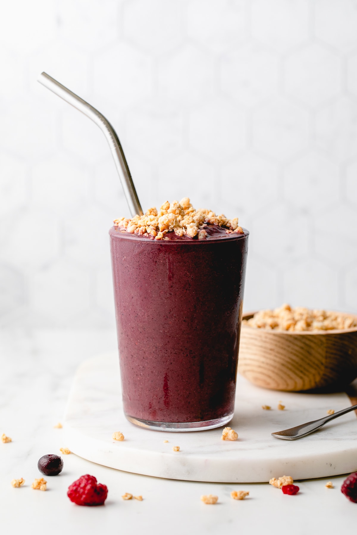 head on view of acai smoothie with spoon and items surrounding.