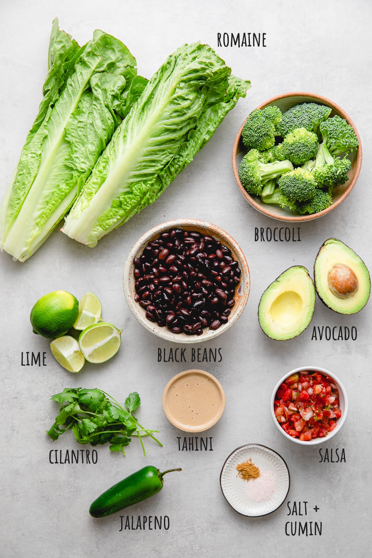 top down view of ingredients used to make black bean broccoli salad with avocado and cumin tahini dressing.