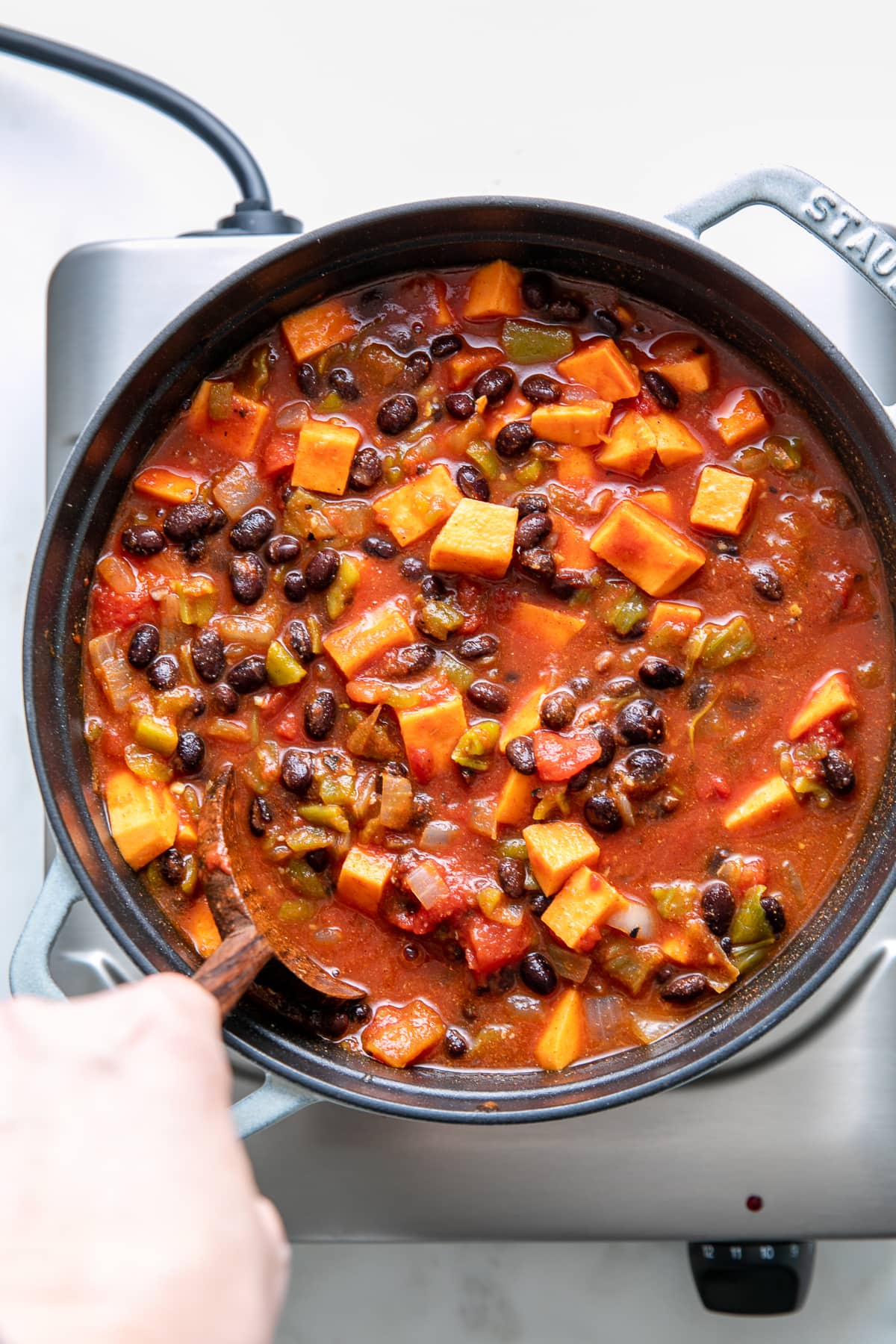 top down view of sweet potato black bean chili stirred in a pot.