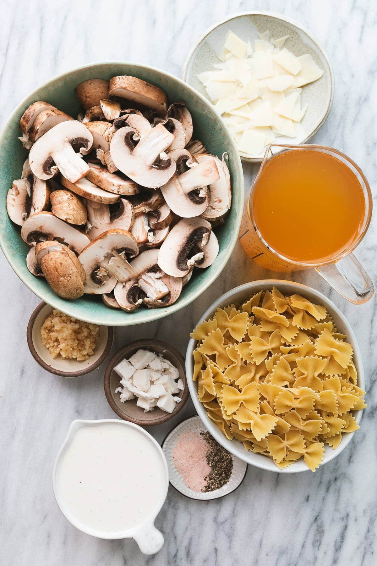 top down view of ingredients used to make creamy vegan mushroom pasta on a marble slab.