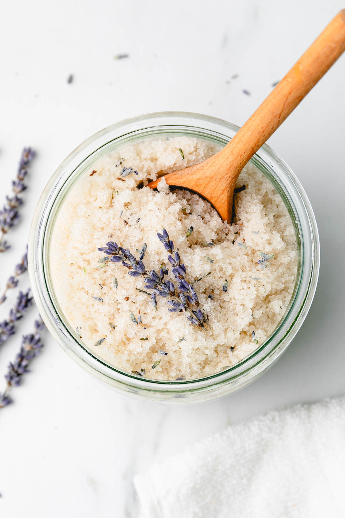 top down view of glass jar with lavender sugar scrub and wooden spoon.
