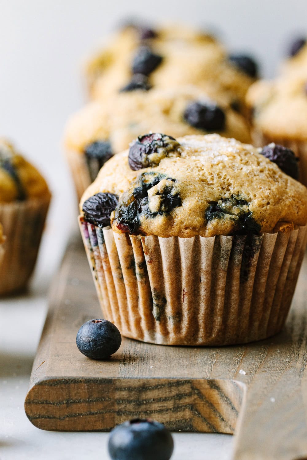 vegan blueberry muffins resting on a wooden board.