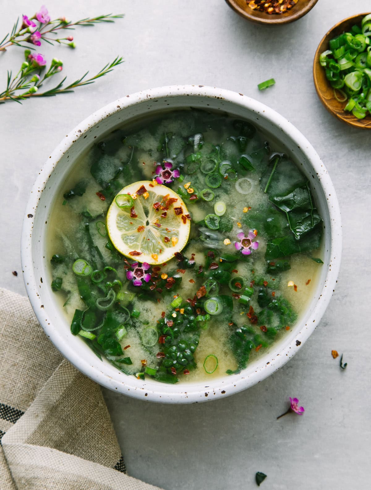vegan clear brothy roasted garlic miso soup in a bowl with items surrounding.