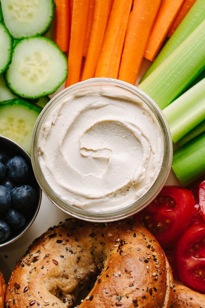 up close of vegan cream cheese platter with fresh fruits, veggies, and bagels.