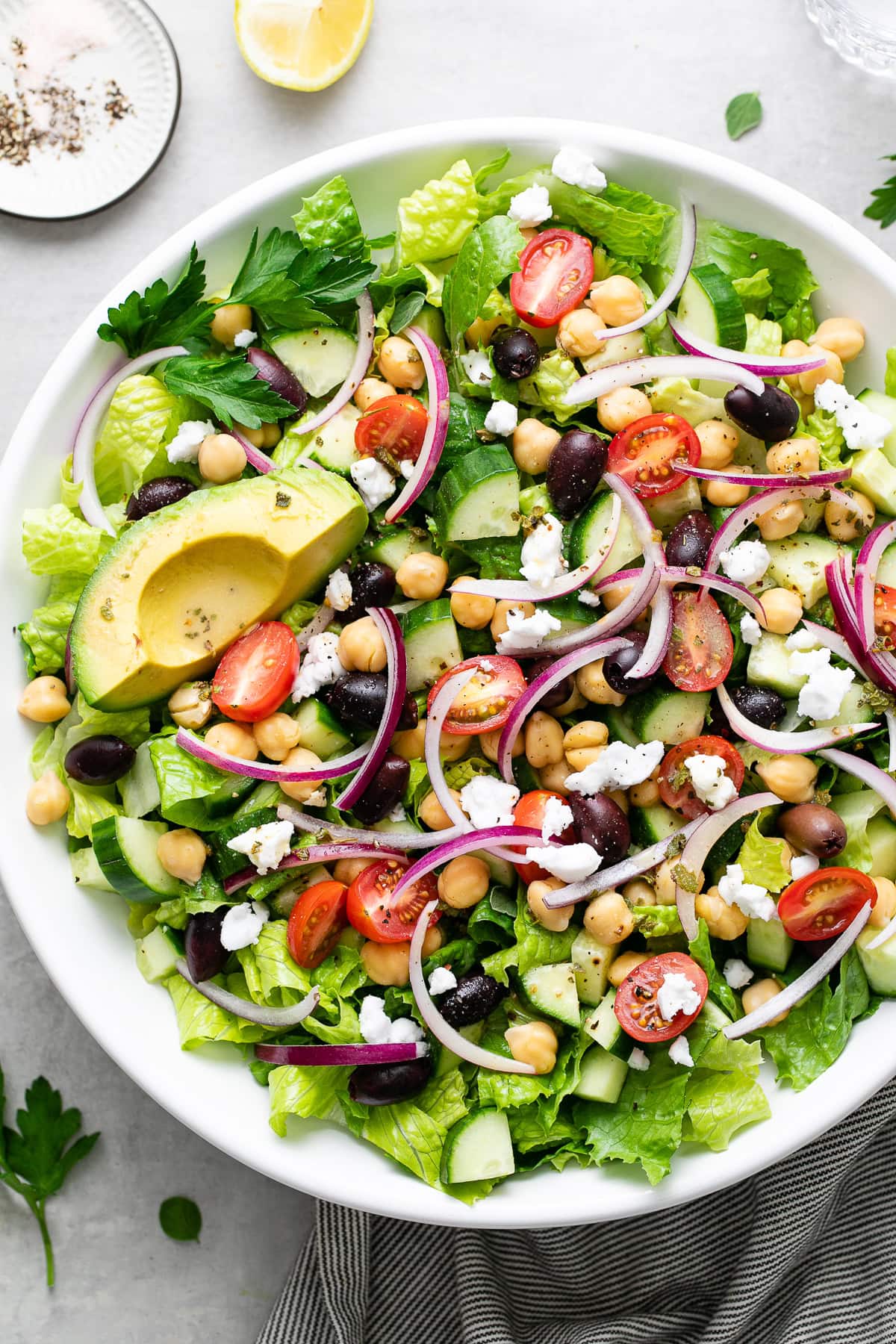 top down view of chopped mediterranean leafy green salad with chickpeas and avocado.