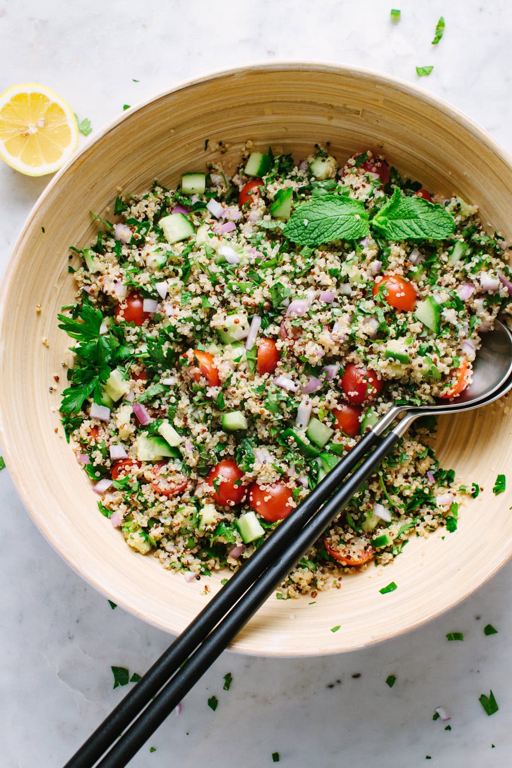 top down view of herbed filled quinoa tabbouleh in a bowl with serving spoons.