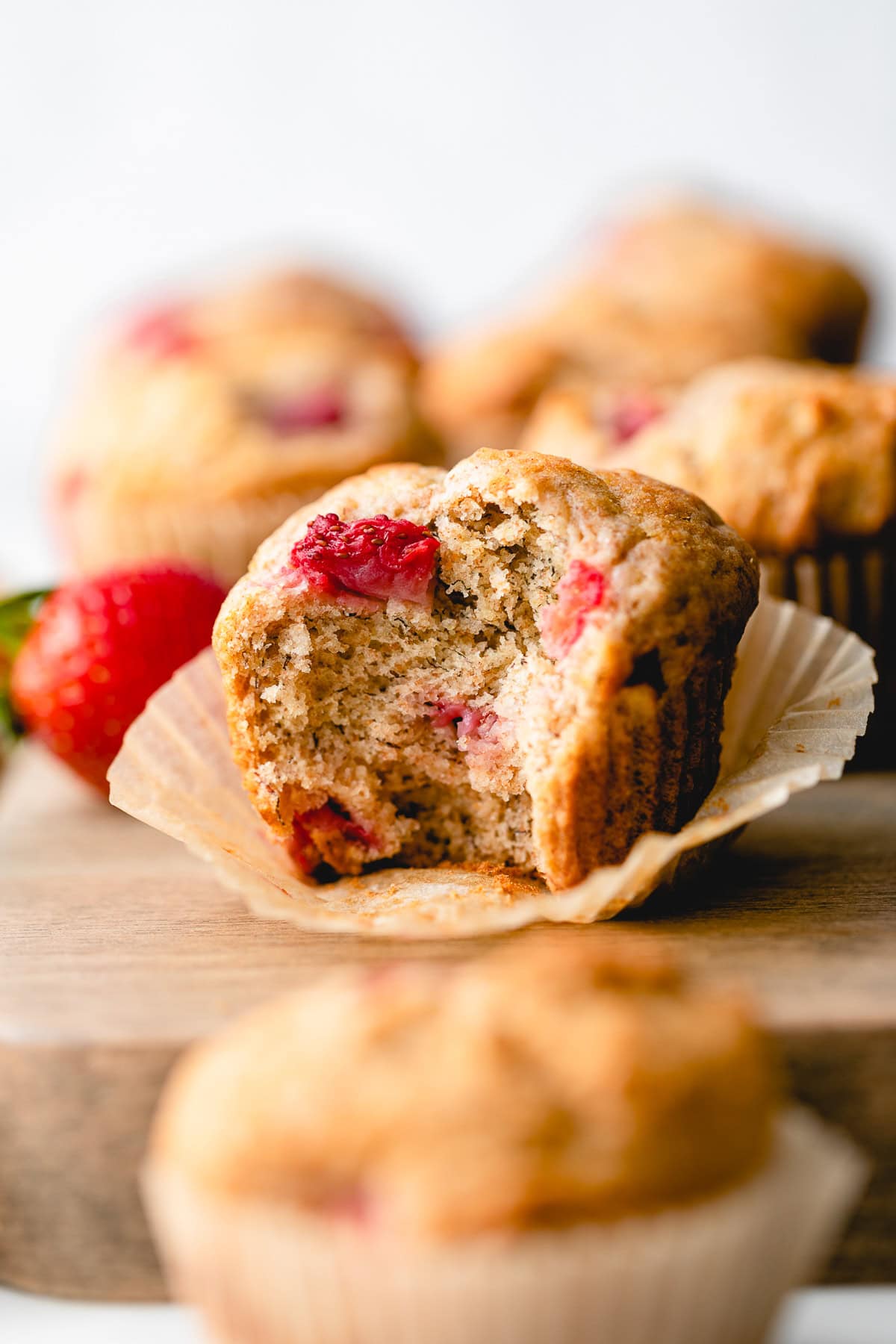 fluffy muffin with bite taken surrounded by other muffins.