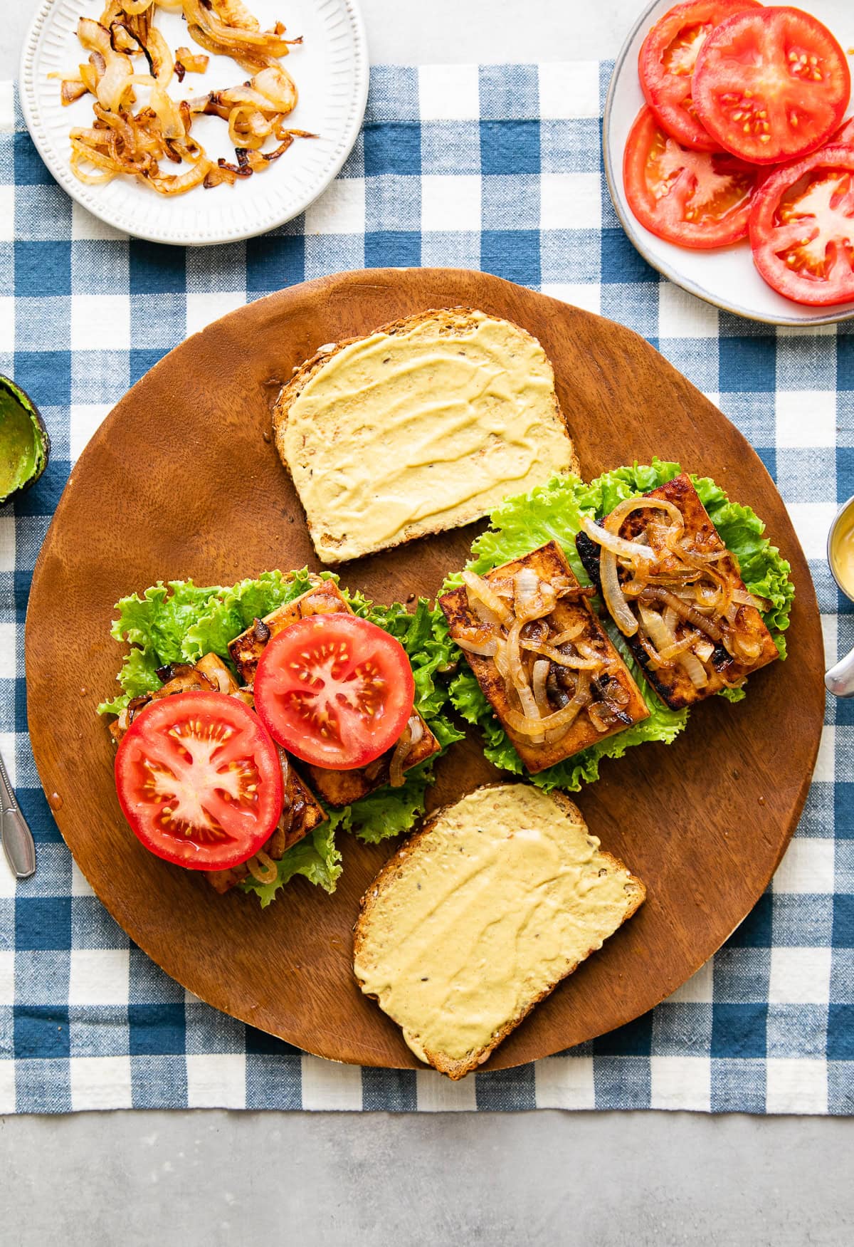 vegan smoky tofu sandwich caramelized onions being prepped on a wooden board. 