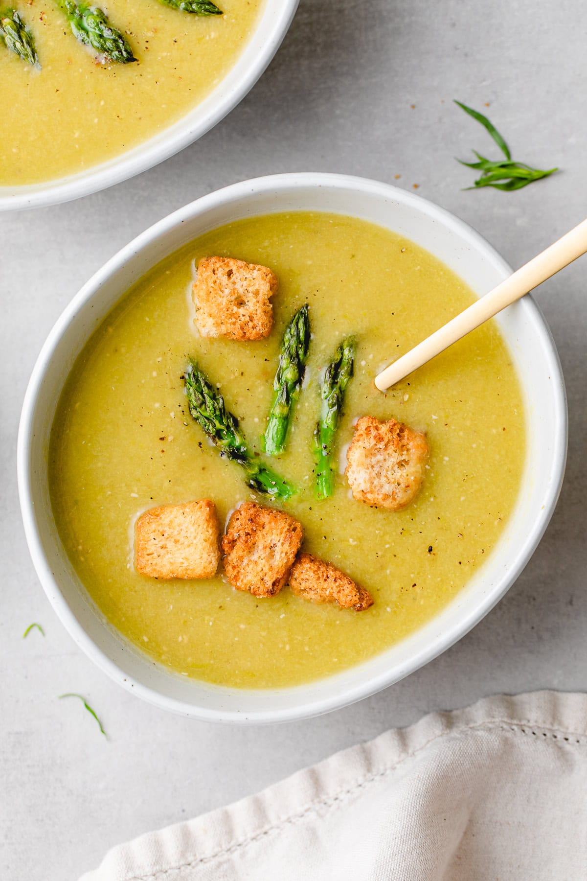 top down view of bowl of vegan asparagus soup with asparagus sprigs and croutons.