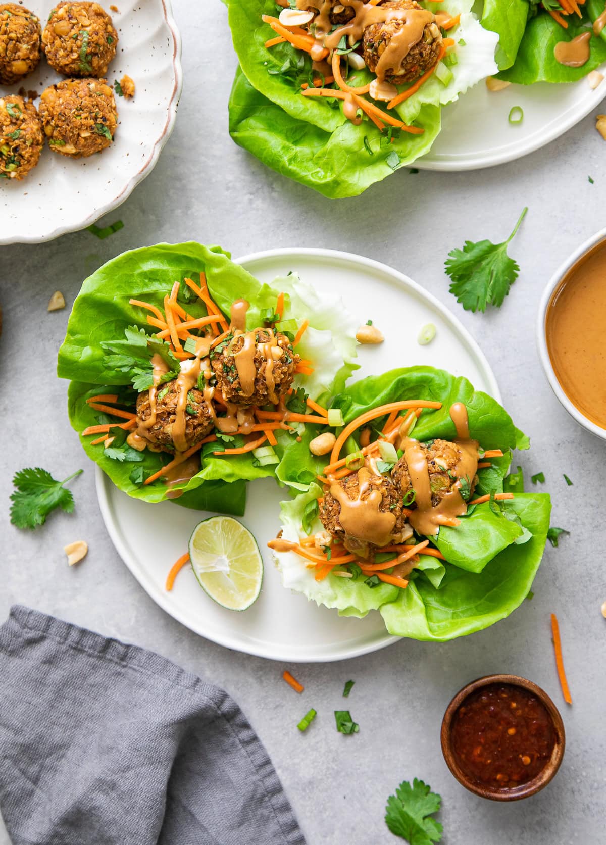 top down view of vegan Thai lettuce wraps with quinoa 'meatballs', shredded carrots and drizzle of peanut sauce.