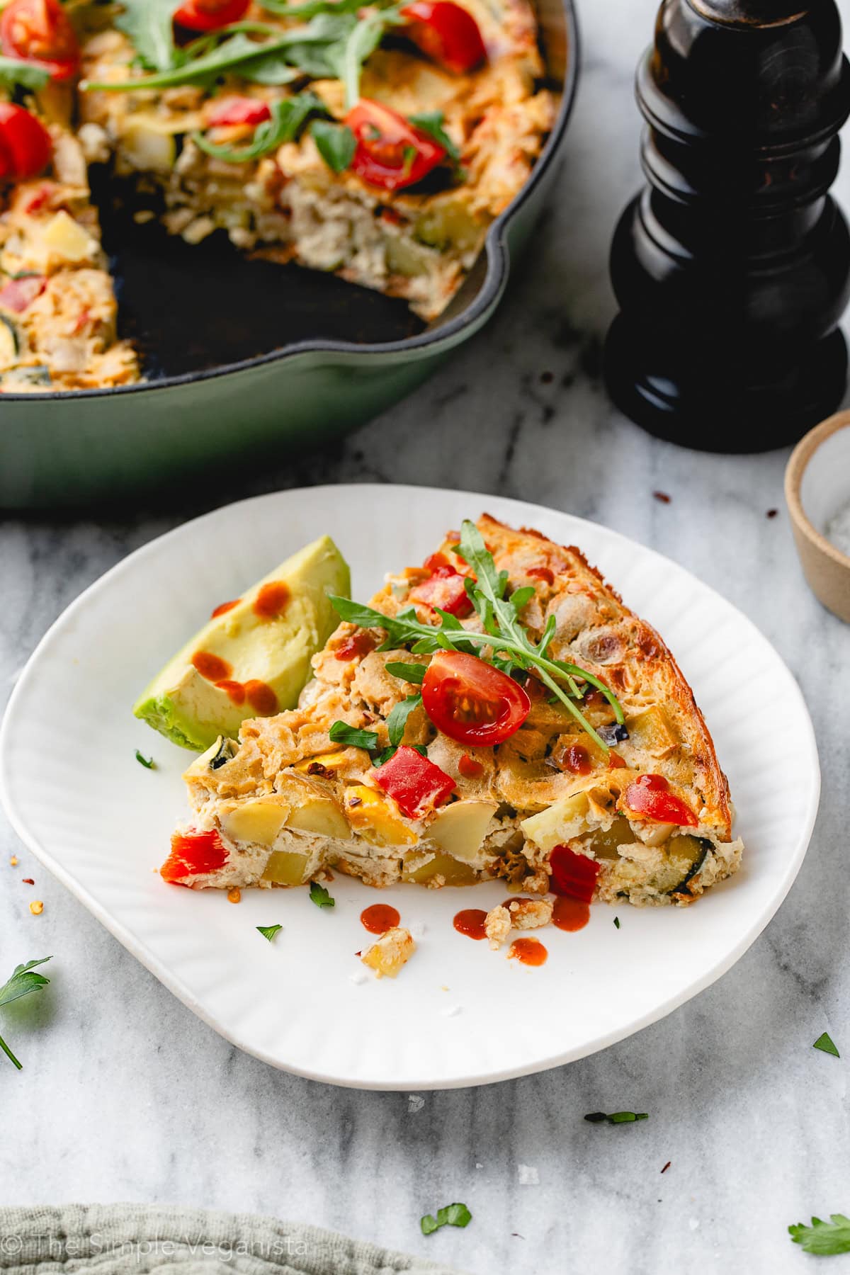 side angle view of plated vegan frittata with items surrounding.