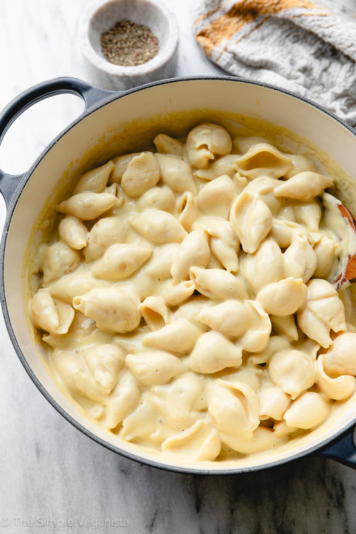 side angle view of freshly made stovetop vegan mac and cheese in a pot with items surrounding.