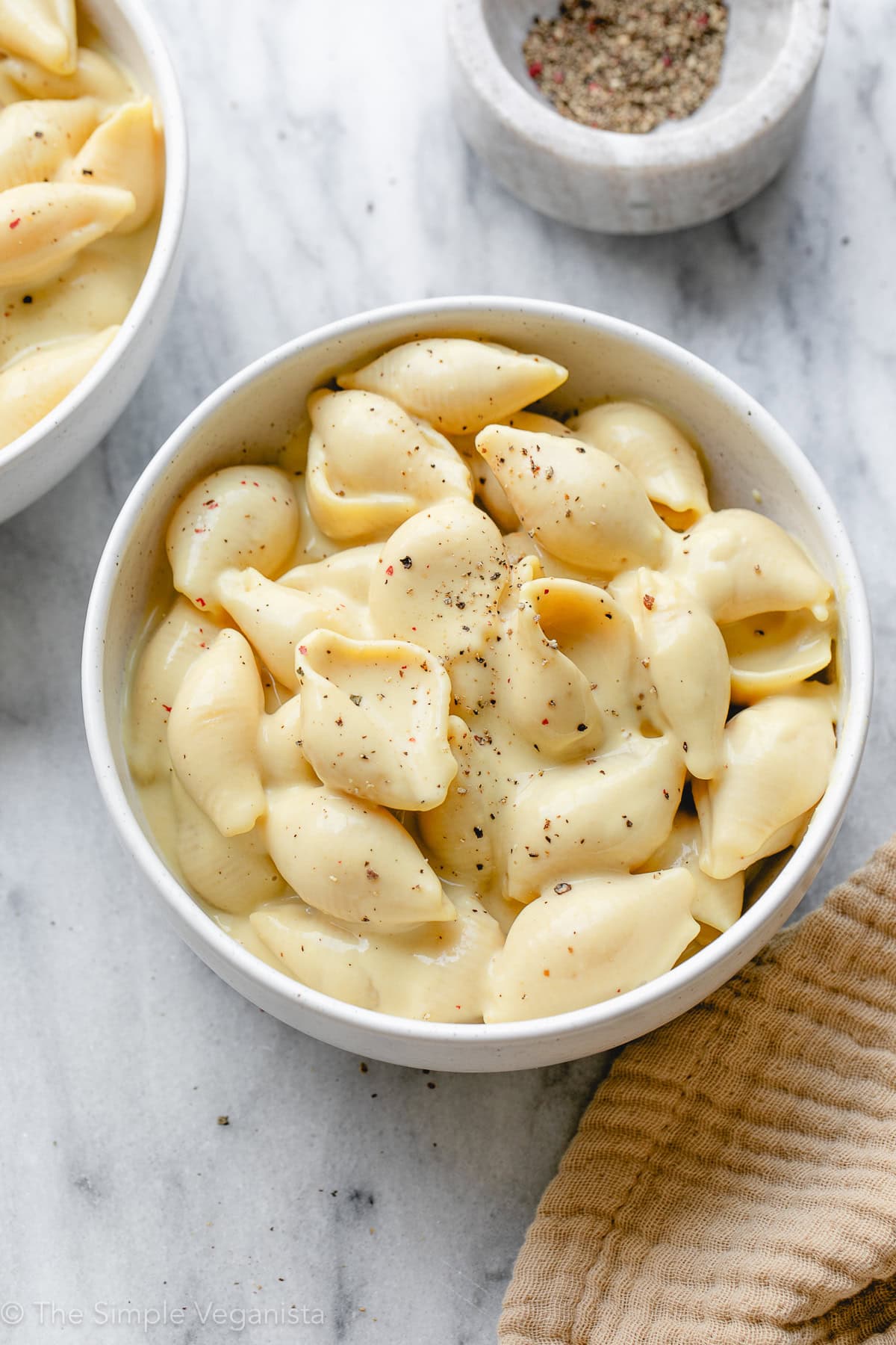 side angle view of bowl of creamy vegan mac and cheese with items surrounding.