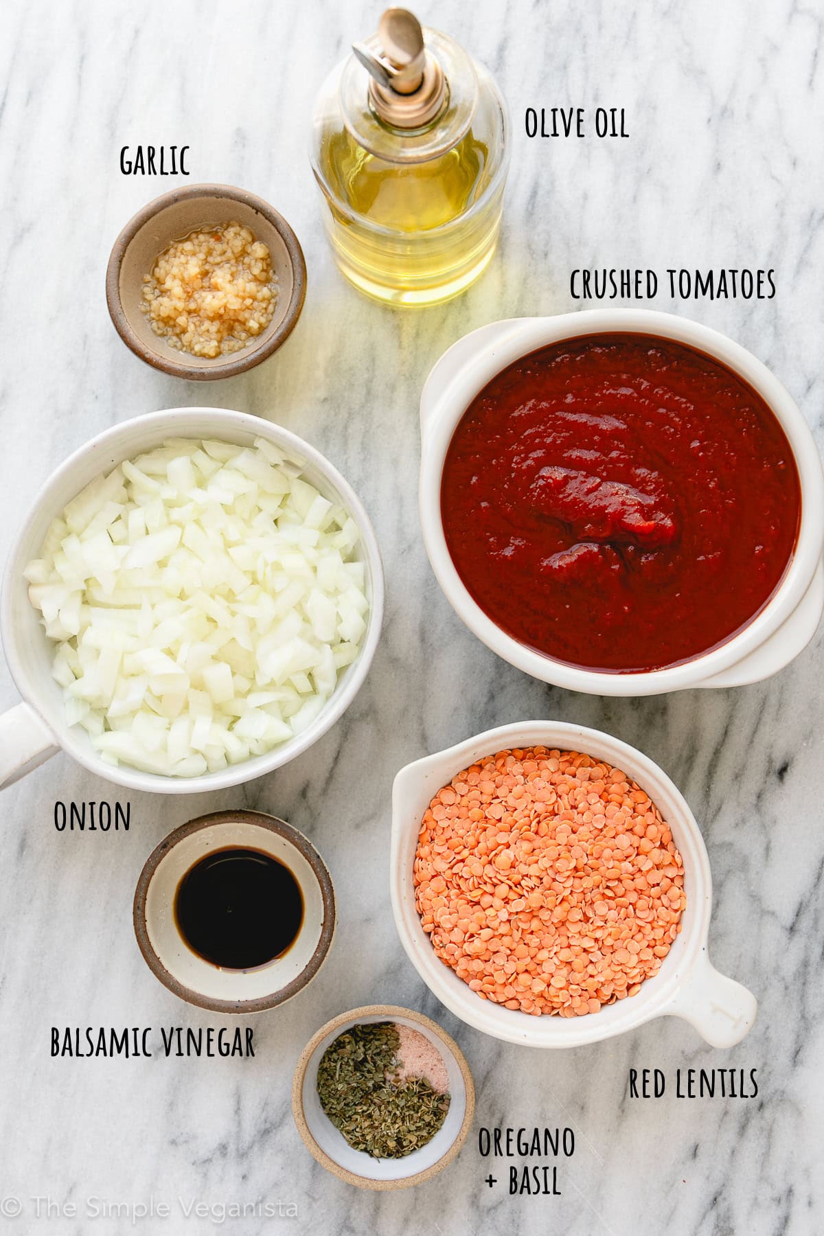top down ingredients used to make red lentil pasta sauce on a marble slab.