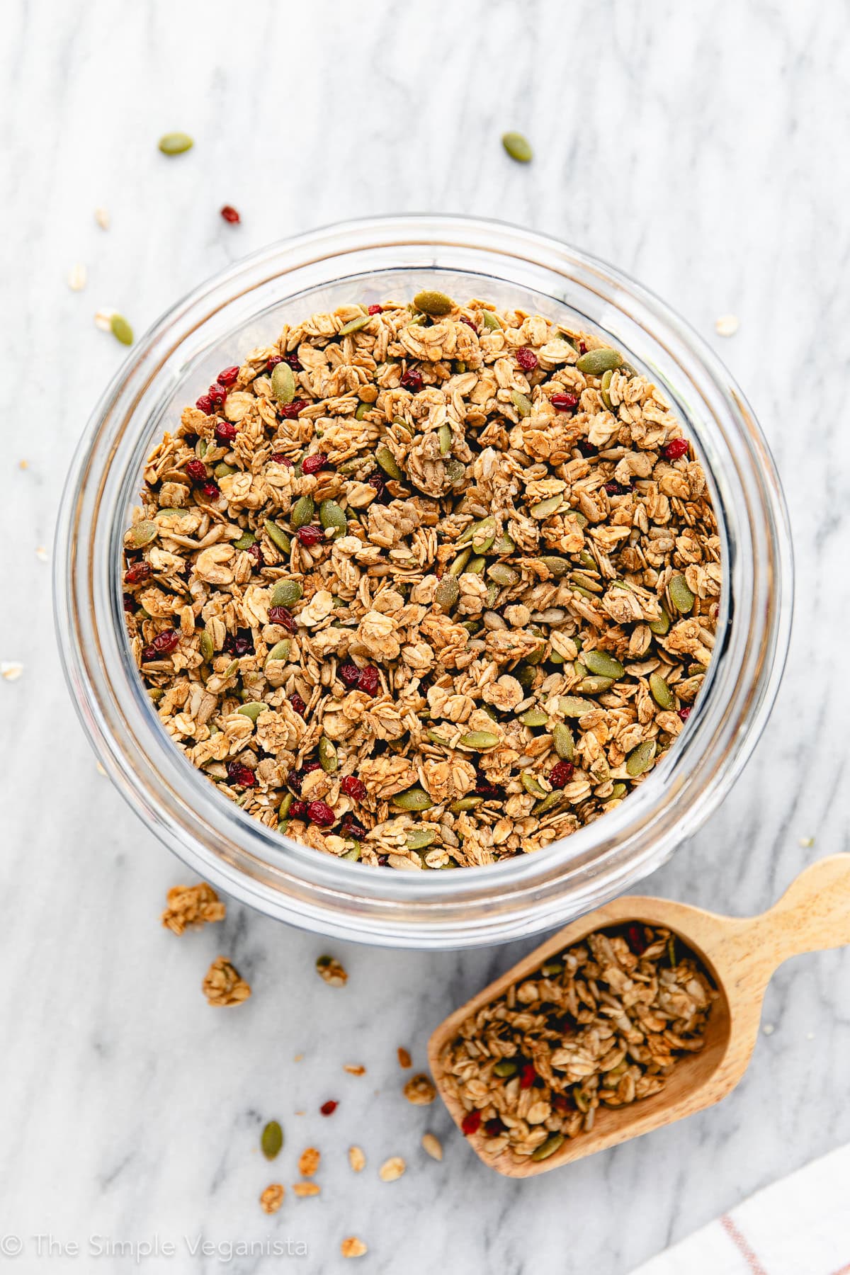 top down view of nut-free granola in a glass jar with wooden scoop.