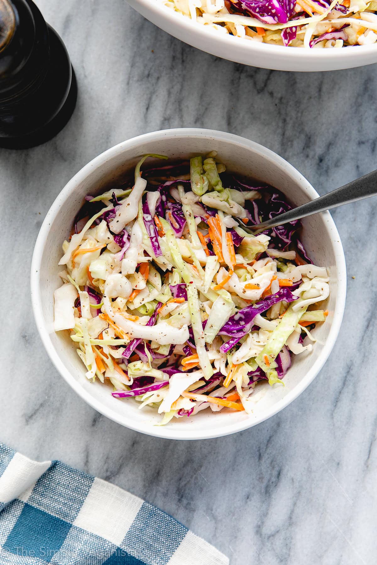 top down view of serving bowl with vegan coleslaw and items surrounding.