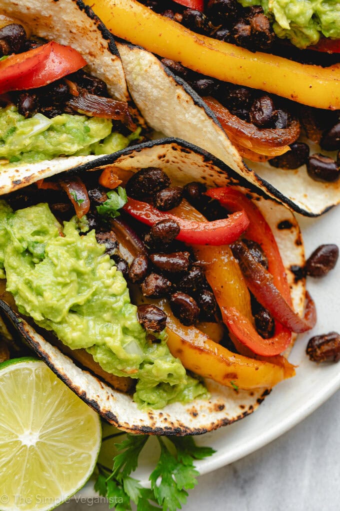 Black bean fajitas served in soft tortillas with avocado, cilantro, and lime.