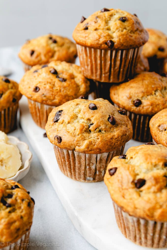 up close view of group of banana muffins with chocolate chips on a marble slab.