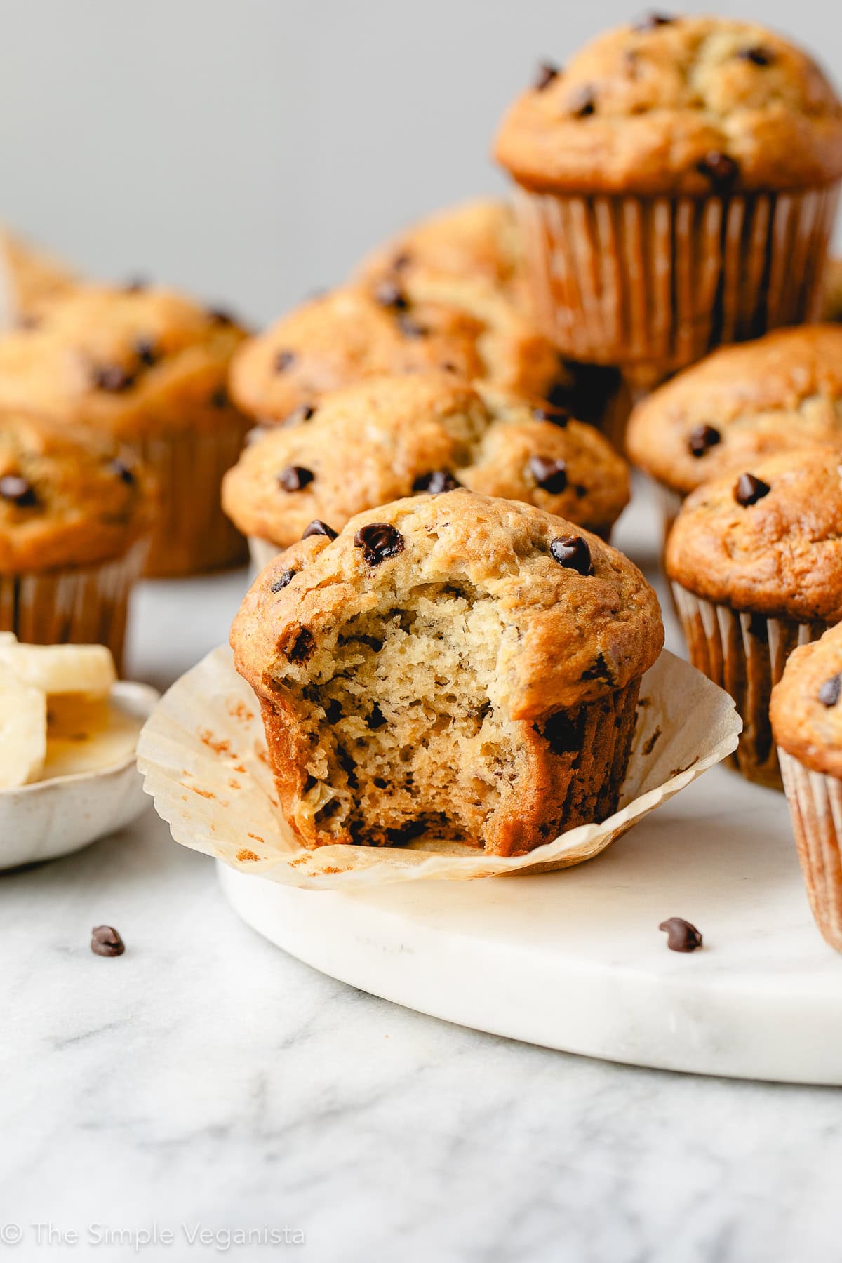 Delicious vegan banana chocolate chip muffins on a white marble surface.