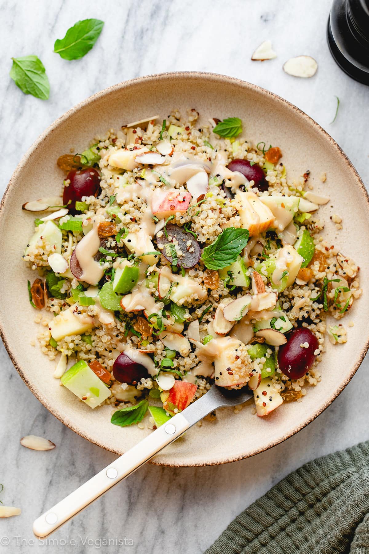 top down view of apple and quinoa salad with sweet tahini dressing in an individual serving bowl.